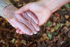 11028621 - young and senior holding hands over autumn leaves